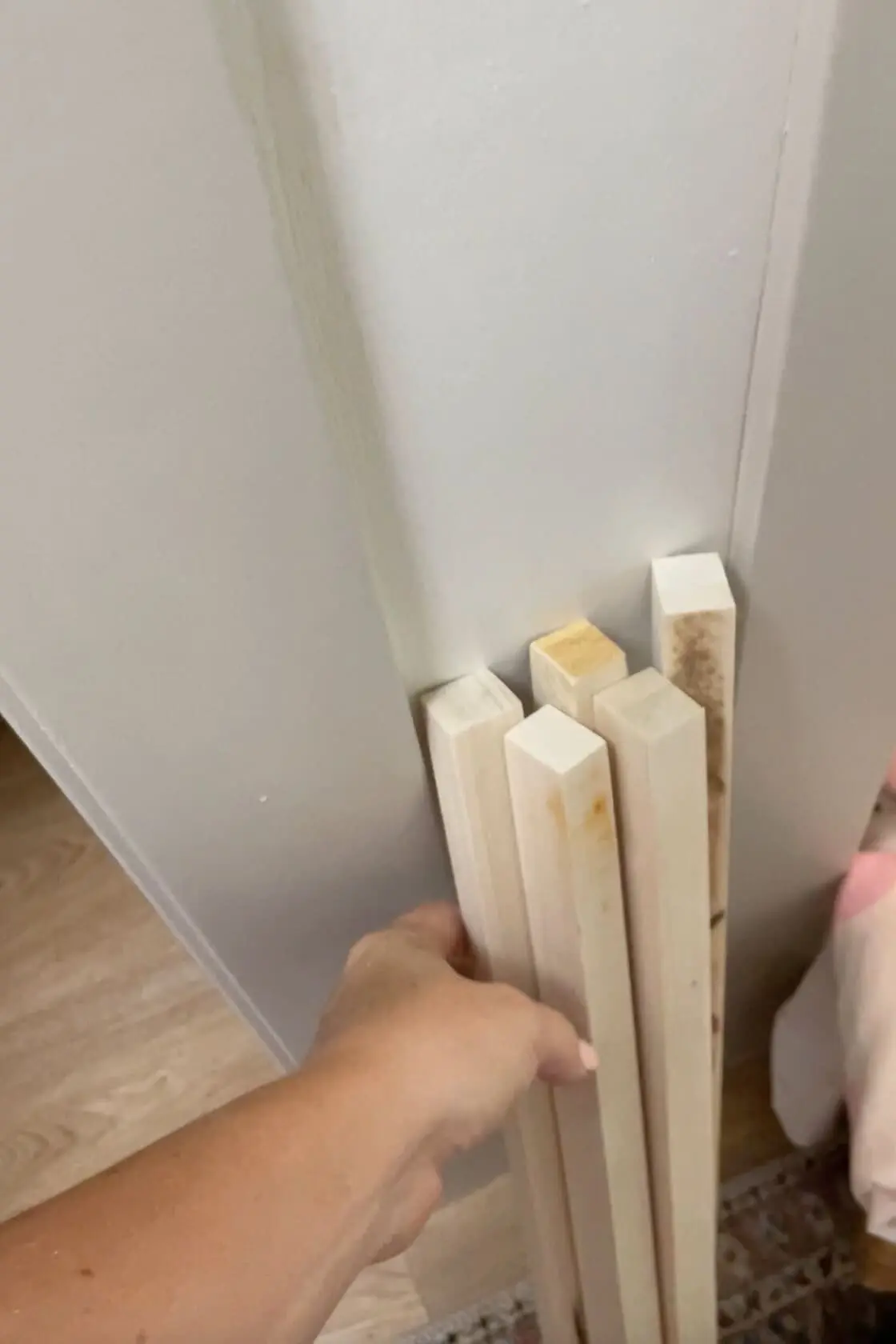 Hand holding wooden boards cut, ready for installation in a DIY project.